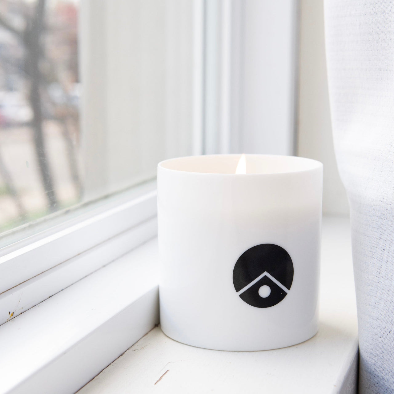white scented candle near the window
